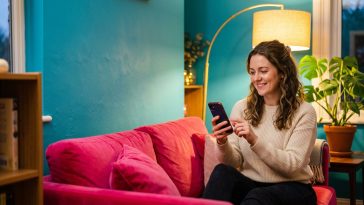 Je me sens seul : une femme sur un canapé fuchsia s'apprête à appeler une amie