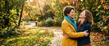 Test amitié : deux amies s'enlacent en riant dans un parc en automne